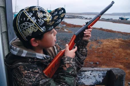 An Inuit boy in Sanikiluaq, Nunavut, uses a pellet gun to hunt for birds